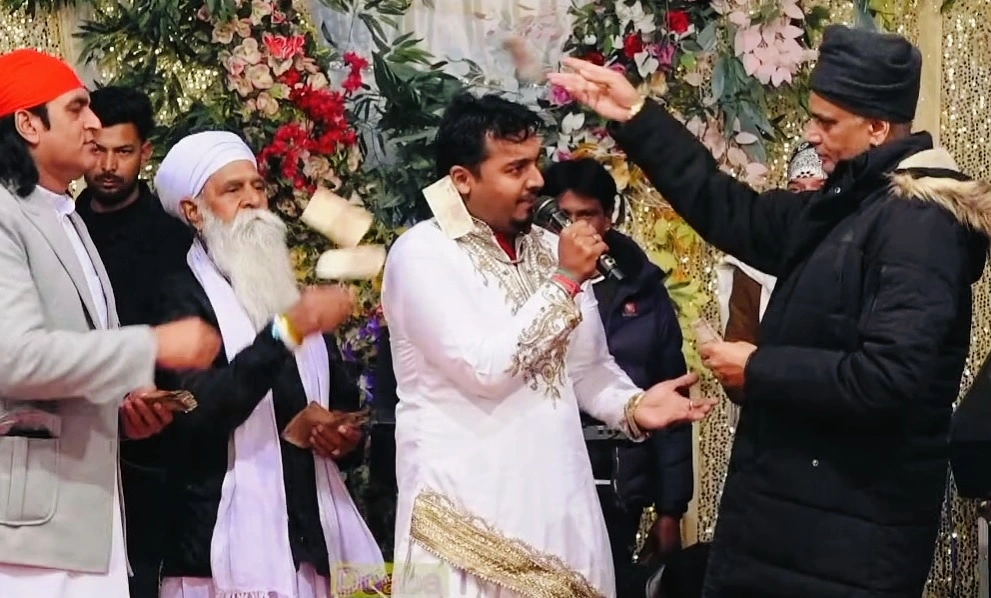 Sidhu Badshah performing at a stage show in white traditional dress